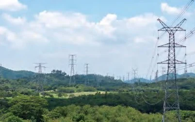 Hochspannungsmasten einer Freileitungstrasse in bewaldetem Hügelland