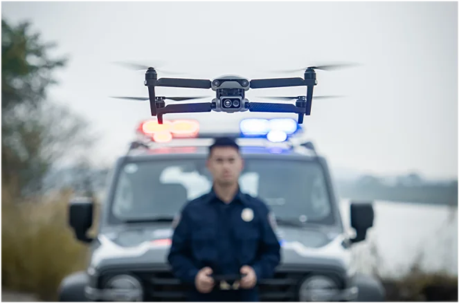 Polizist mit Controller vor einem Einsatzfahrzeug, darüber die Drohne