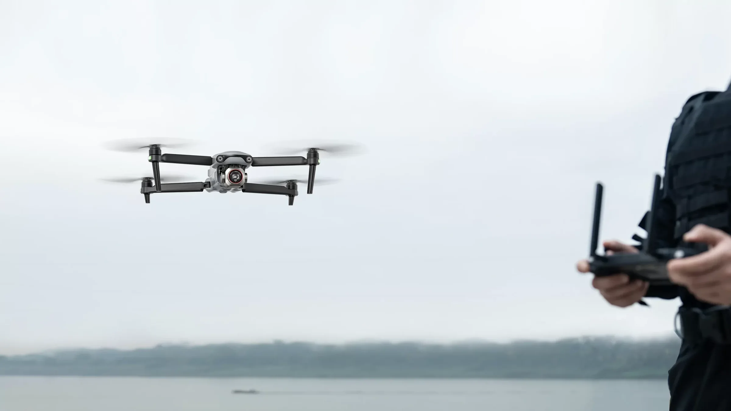 EVO Lite Enterprise über einem See, Pilot mit Controller im Vordergrund